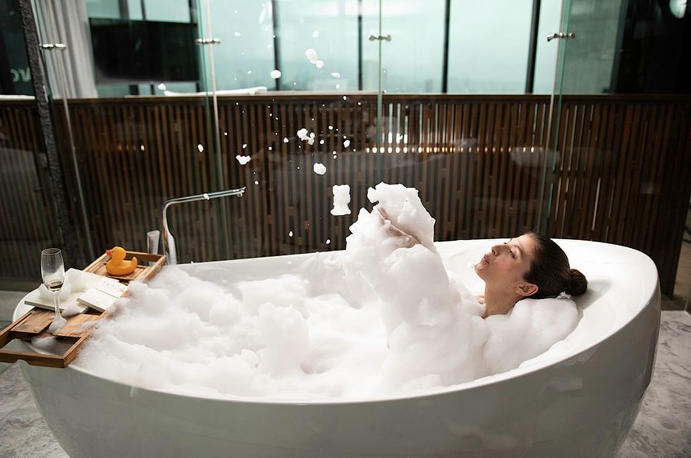 A woman in the bathtub overflowing with bubbles at Live Aqua Resorts and Residence Club