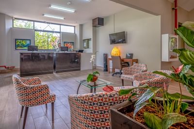 Lobby area with front desk, lounge chairs, coffee table & TV at Irazu Hotel