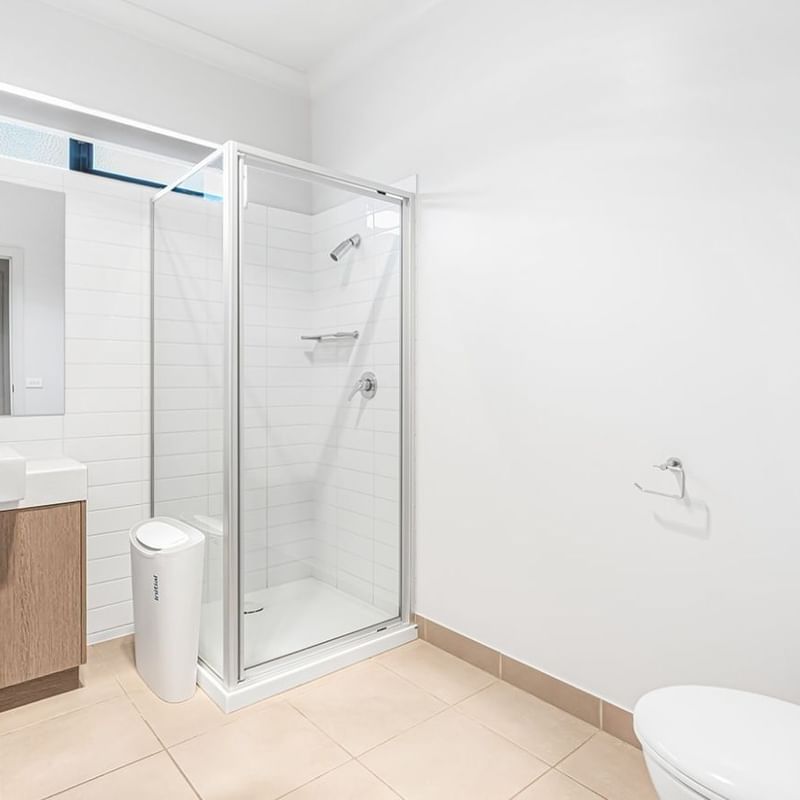 Modern bathroom with toilet, sink, mirror, and shower stall at La Trobe University Regional Housing – Mildura.