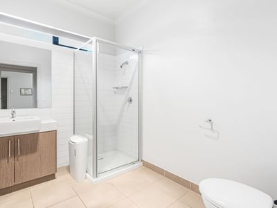 Modern bathroom with toilet, sink, mirror, and shower stall at La Trobe University Regional Housing – Mildura.