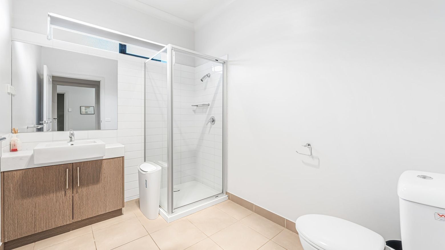 Modern bathroom with toilet, sink, mirror, and shower stall at La Trobe University Regional Housing – Mildura.