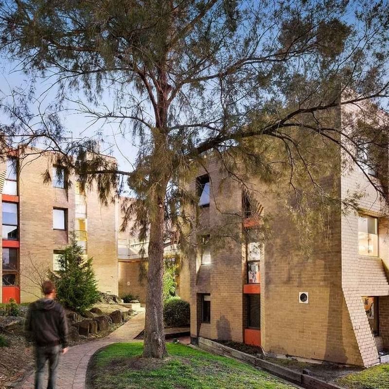 Person walking on pathway by La Trobe University - Chisholm College building.