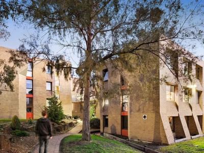 Person walking on pathway by La Trobe University - Chisholm College building.