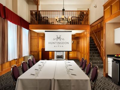8-seat boardroom set up with a projector screen at Huntingdon Manor