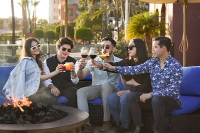 Friends toasting wine by a campfire at Hotel Coral y Marina
