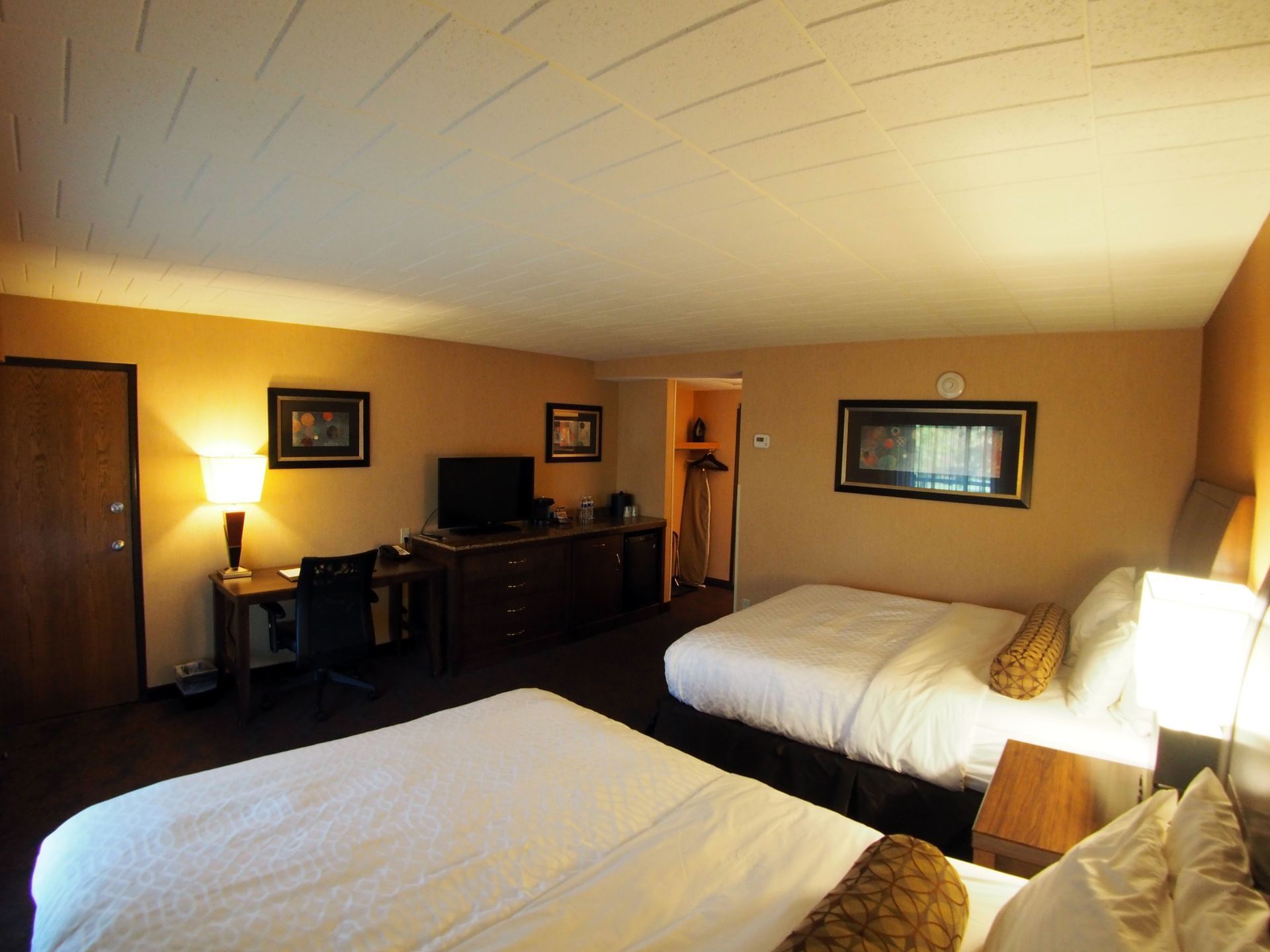 Room with two queen beds, desk, and television at Evergreen Resort in Cadillac.