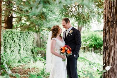 Bride and groom looking lovingly into each others eyes in a gard