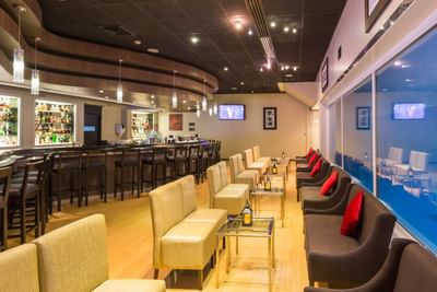 Oceanus Lounge interior with plush seating, bar counter, and bar shelves at Hotel Los Delfines & Casino