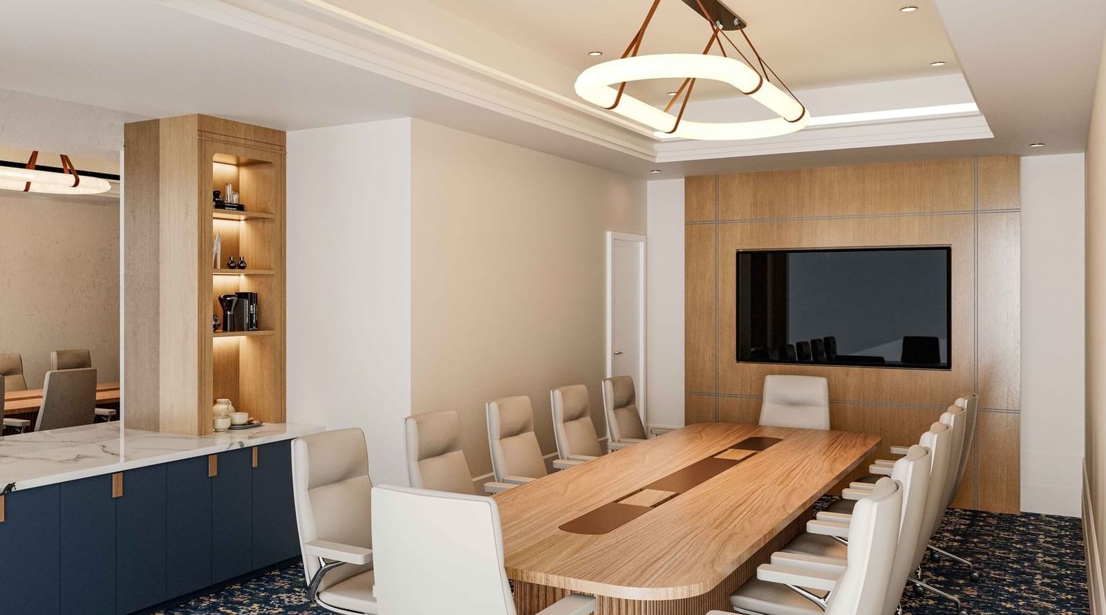 Boardroom set-up facing a wall-mounted TV and a bookshelf at El Prado Hotel