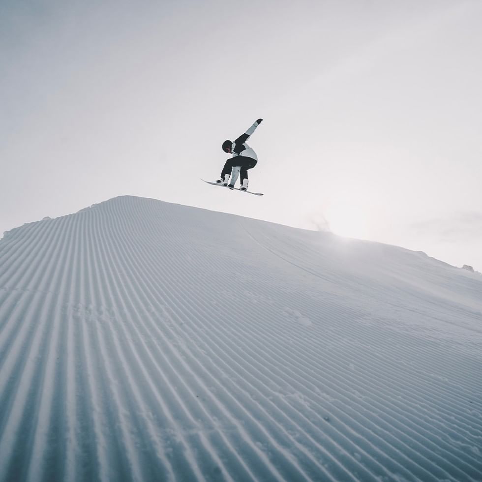Snowboarder performing a jump over a snowy slope.