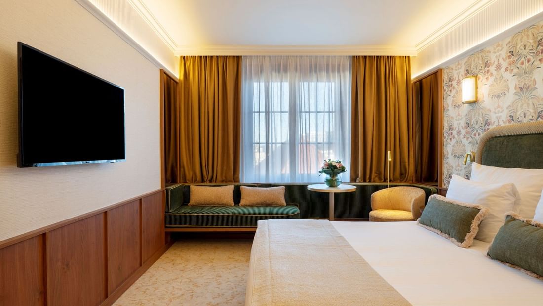 Superior Room with white bed, green and gold accents, window seating, and flat-screen TV at Warwick Brussels Grand-Place