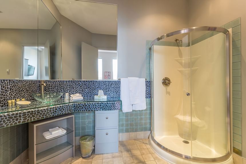 bathroom with rounded corner shower and pebble tile backsplash
