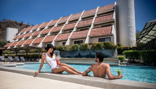 Couple lounging in the outdoor pool at Villas Sol Beach Resort