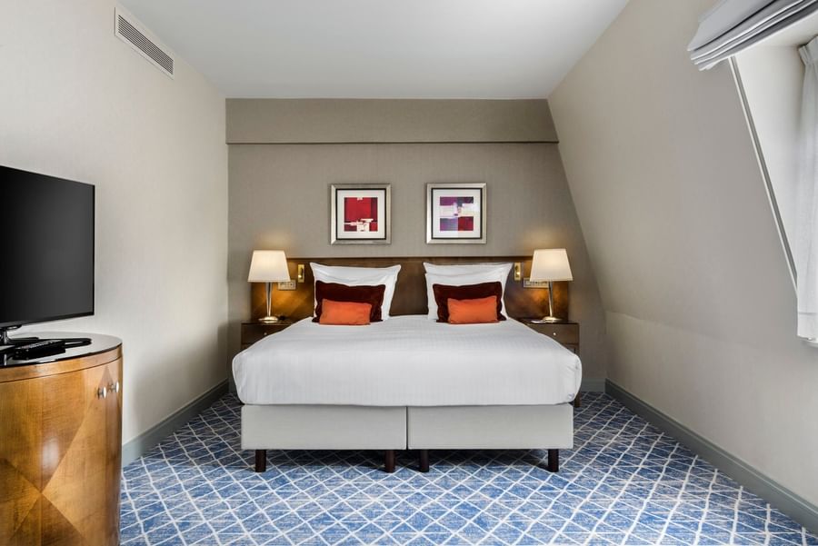 Ruime hotelkamer met tweepersoonsbed en moderne inrichting.