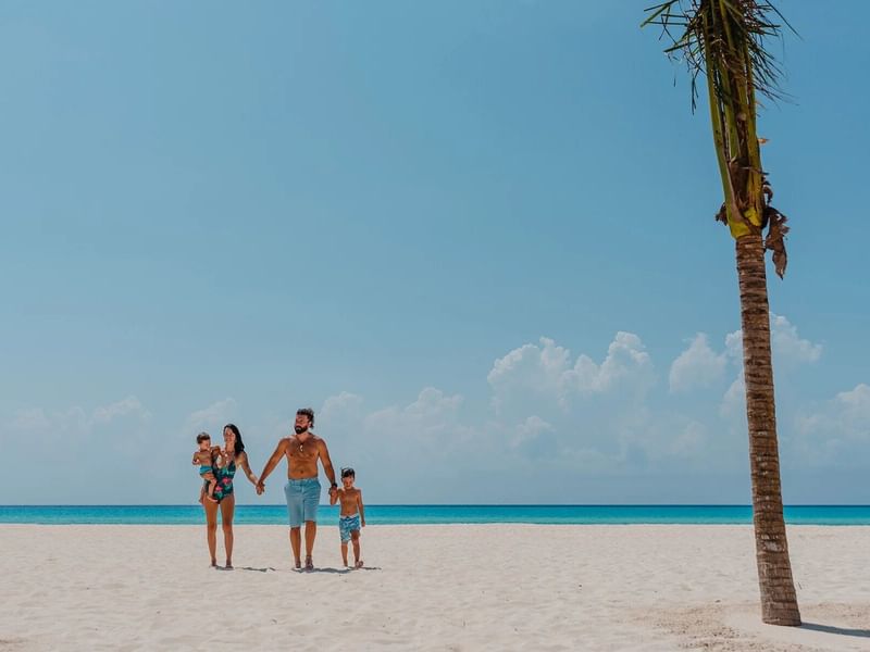 A family walking on the beach at  The Reef Playacar