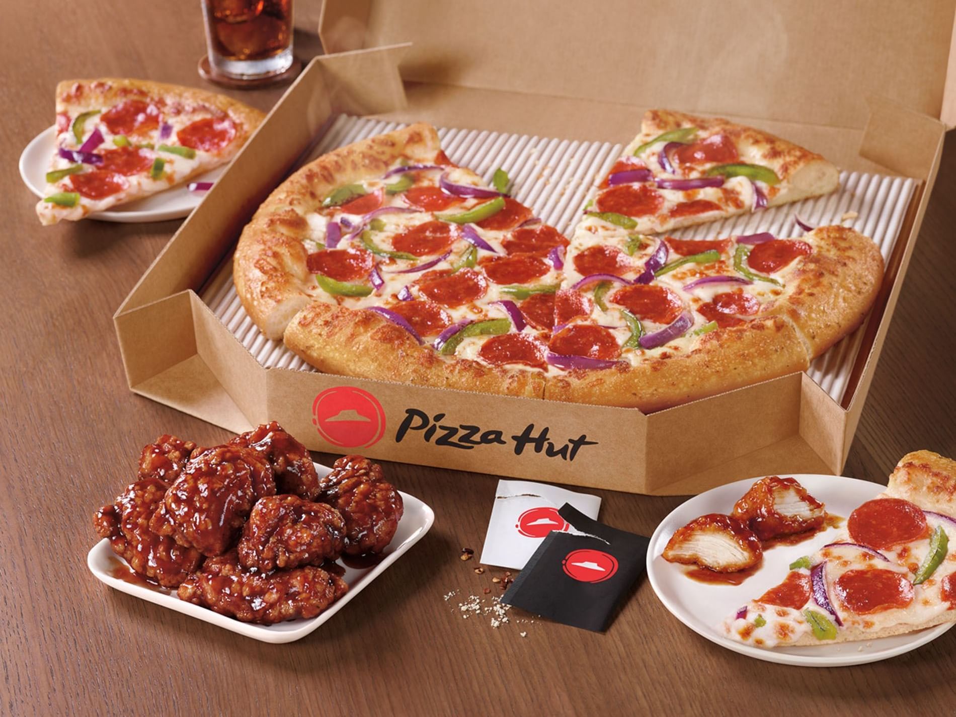 A table with a Pizza Hut pizza and chicken.