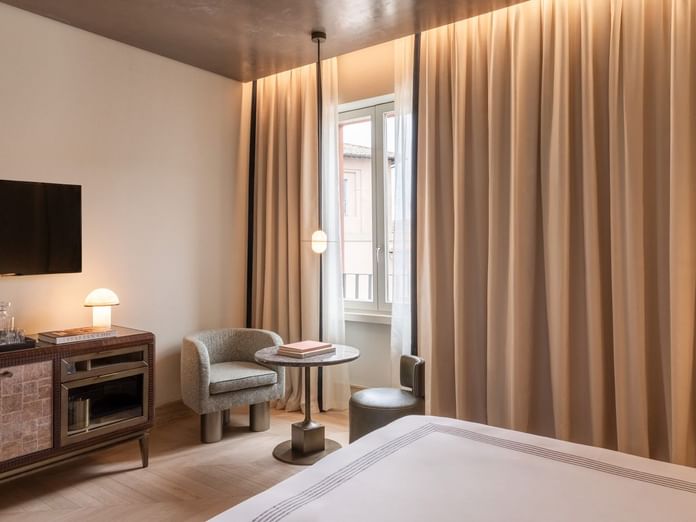 King bed room with seating area, floor-to-ceiling curtains, and city view window at The Thompson Rome, Roma.