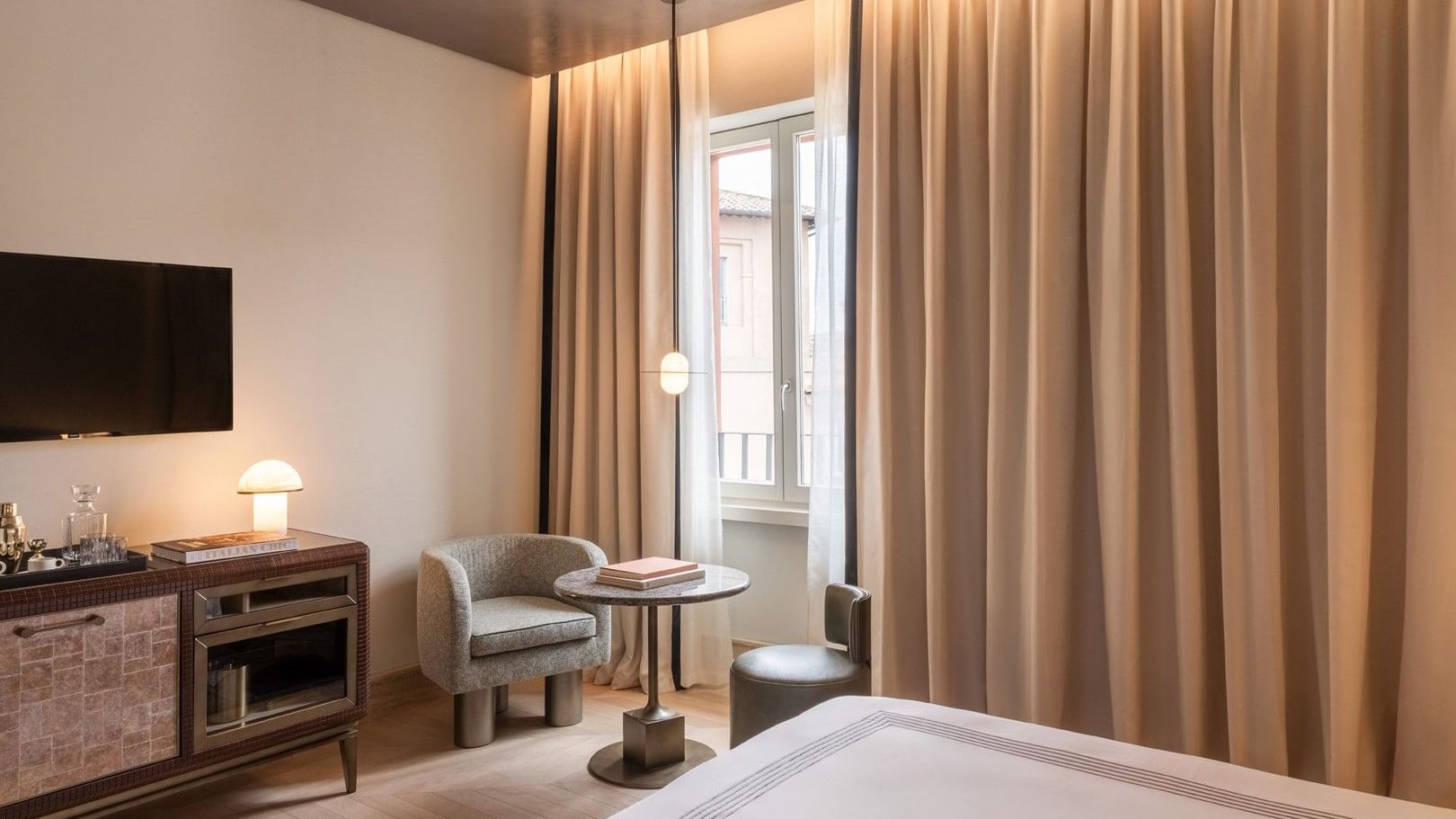 King bed room with seating area, floor-to-ceiling curtains, and city view window at The Thompson Rome, Roma.