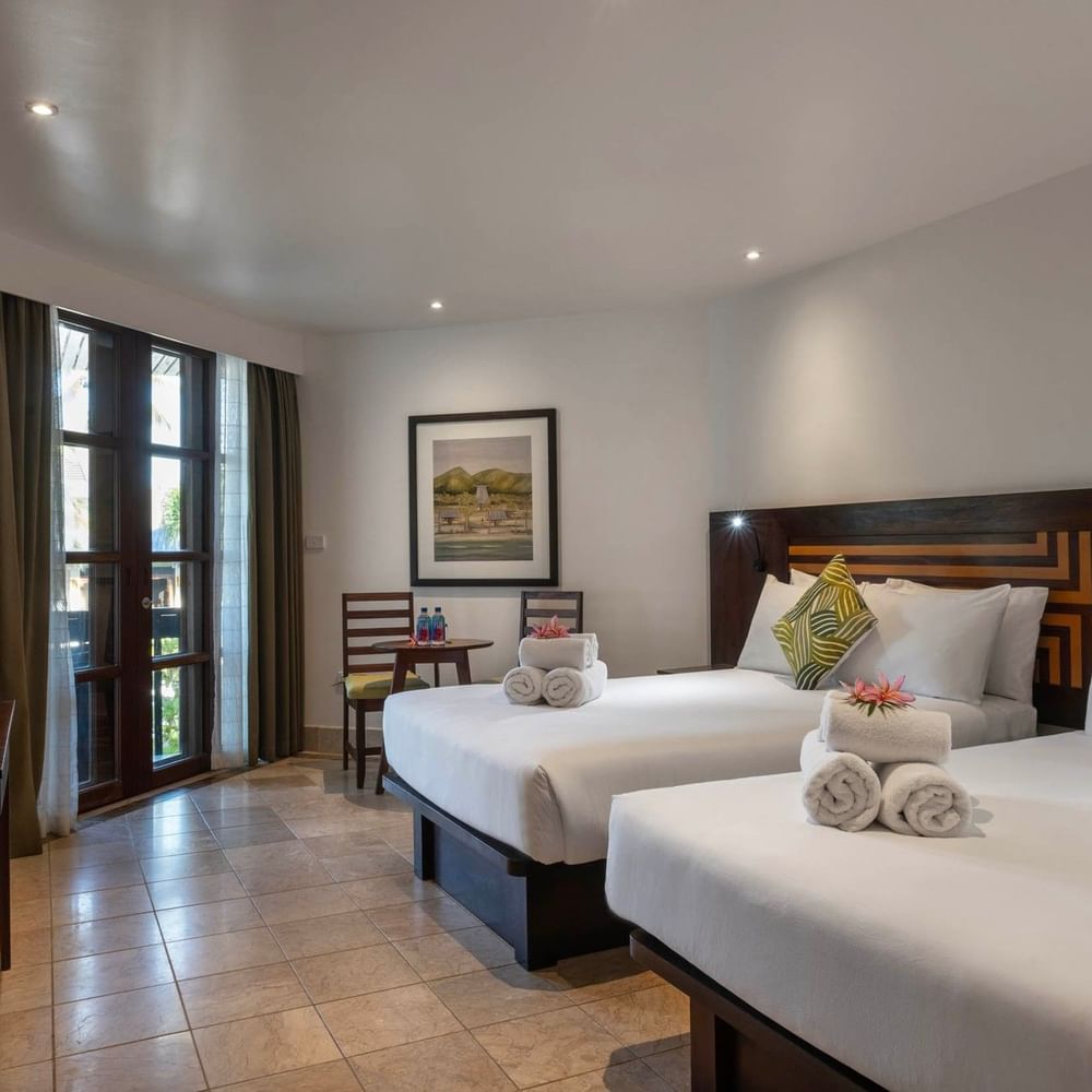 Two Warwick Deluxe Rooms with white bedding and balcony at Warwick Fiji Resort and Spa, Korolevu.