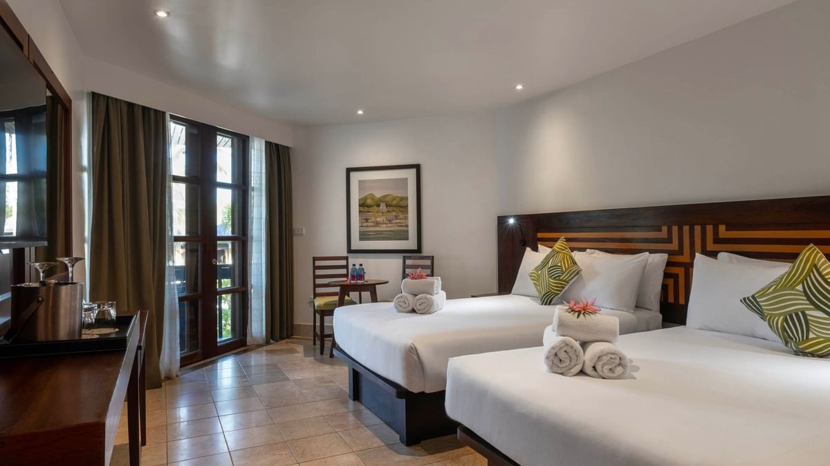 Two Warwick Deluxe Rooms with white bedding and balcony at Warwick Fiji Resort and Spa, Korolevu.