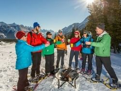 A group of friends in winter clothes gathered around a firepit near Acclaim Hotel Calgary