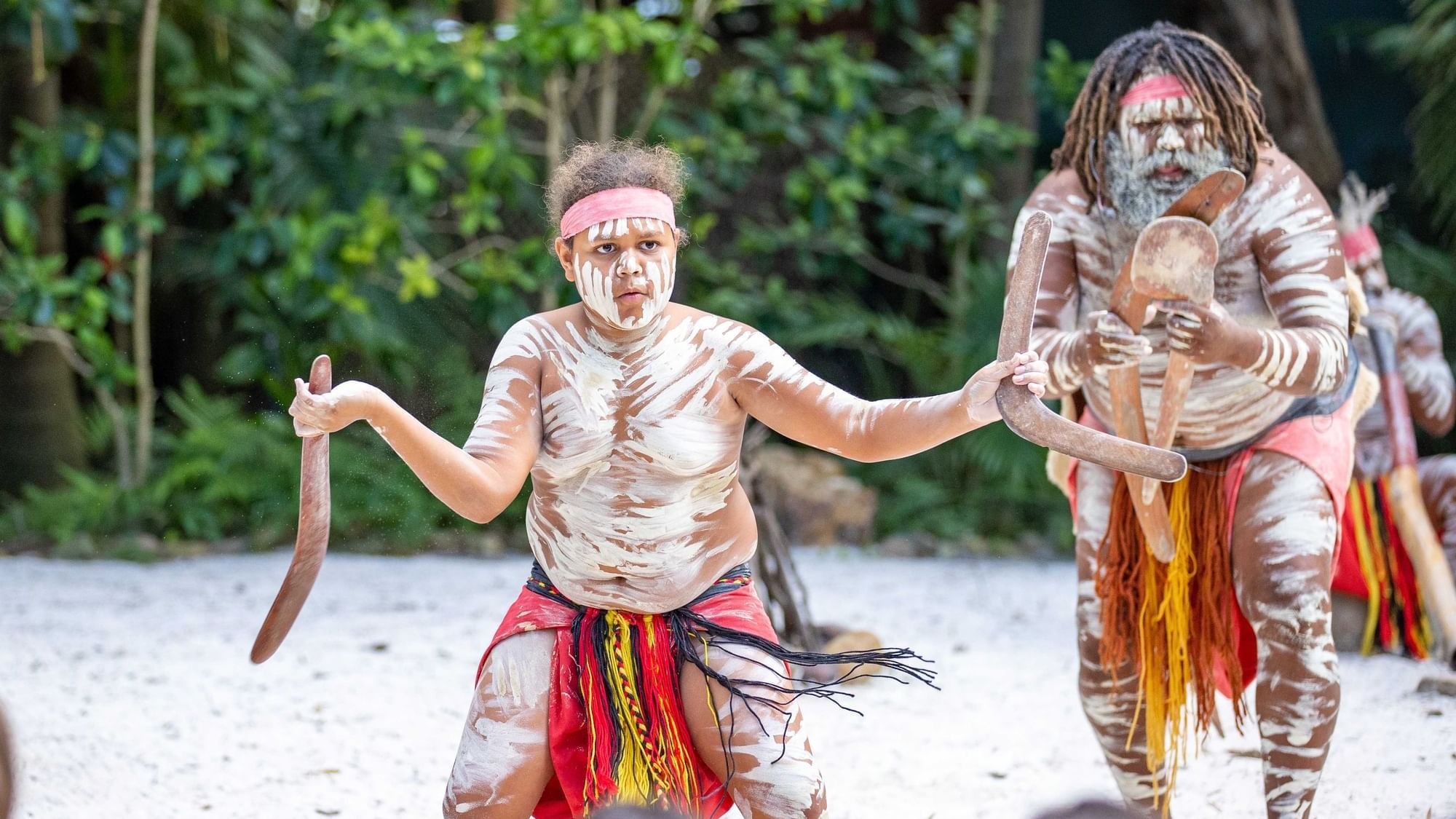 First Nations people in traditional dress and body paints performing on a beach near Sofitel Brisbane Central
