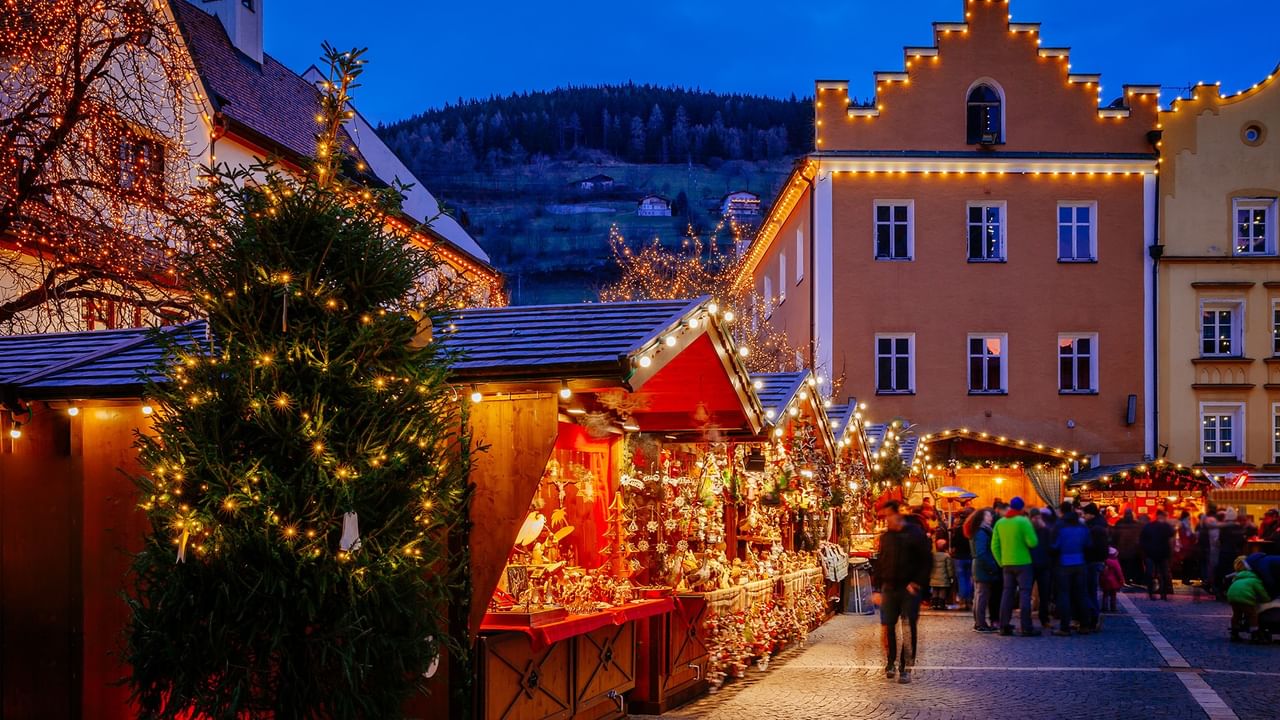 Langley Christmas Village with illuminated market stalls, decorated trees and festive crowds.