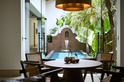 Dining table with chairs and decorative fruit centerpiece, overlooking a pool in Casa Cielo at Singular Signature Residences