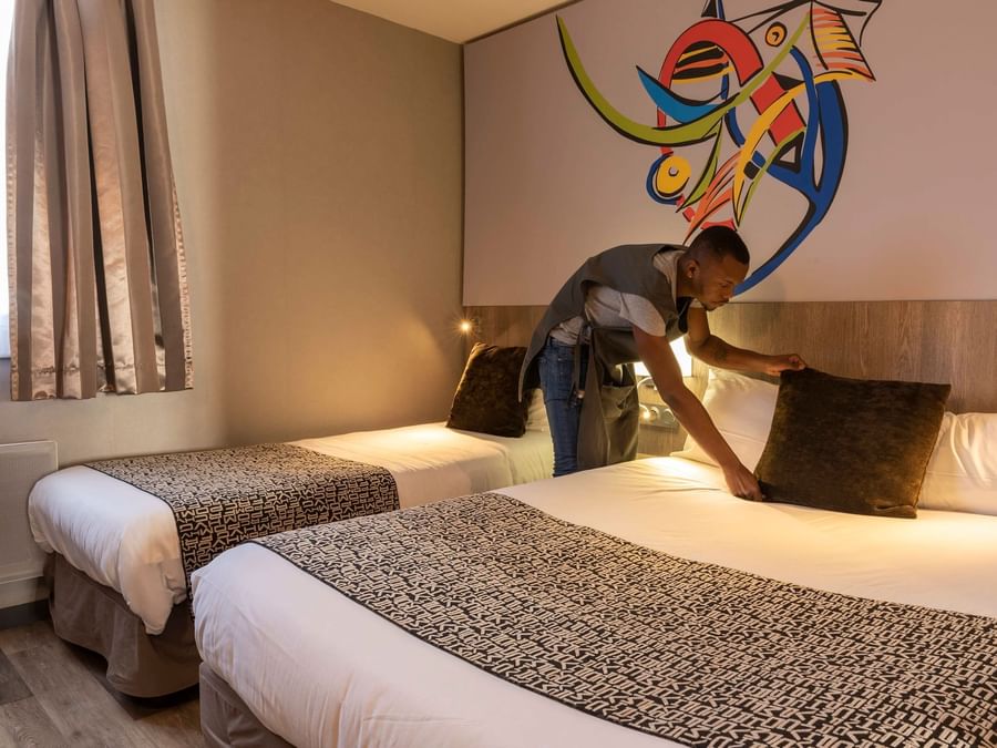 A man preparing a Standard Double bed at Hotel La Terrasse