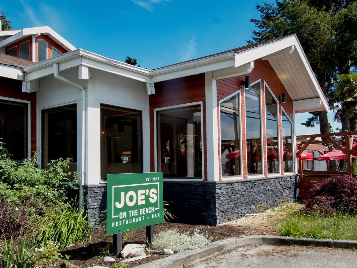Joe's On The Beach Restaurant & Bar building with a green sign in front and outdoor seating area.