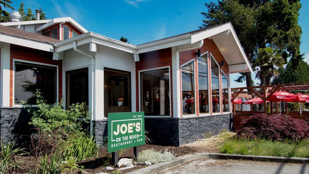 Joe's On The Beach Restaurant & Bar building with a green sign in front and outdoor seating area.