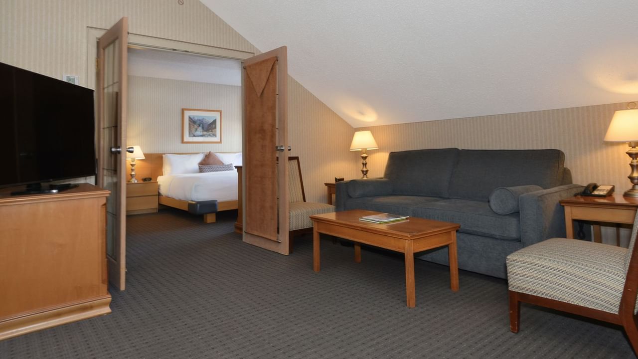 Spacious hotel suite with a king bed, elegant decor, and sofa bed.