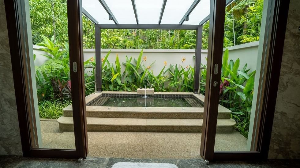 Private outdoor hot spring jacuzzi with glass roof and tropical garden views in the Royal Villa at The Banjaran Hotsprings Retreat