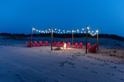 Beach bonfire with red chairs at night, perfect for PEI beach wedding events at Rodd Crowbush Golf & Beach Resort