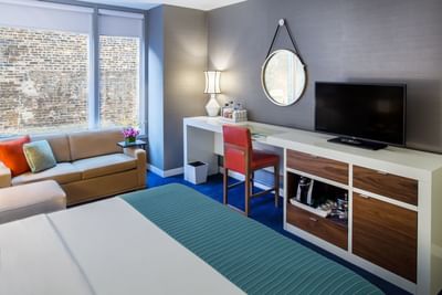 Bed, work desk, TV & a sofa in Deluxe King Room at Kinzie Hotel