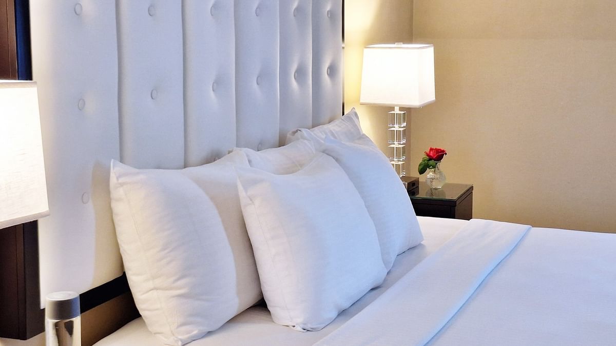A neatly made bed with white bedding and pillows at Warwick Allerton - Chicago.