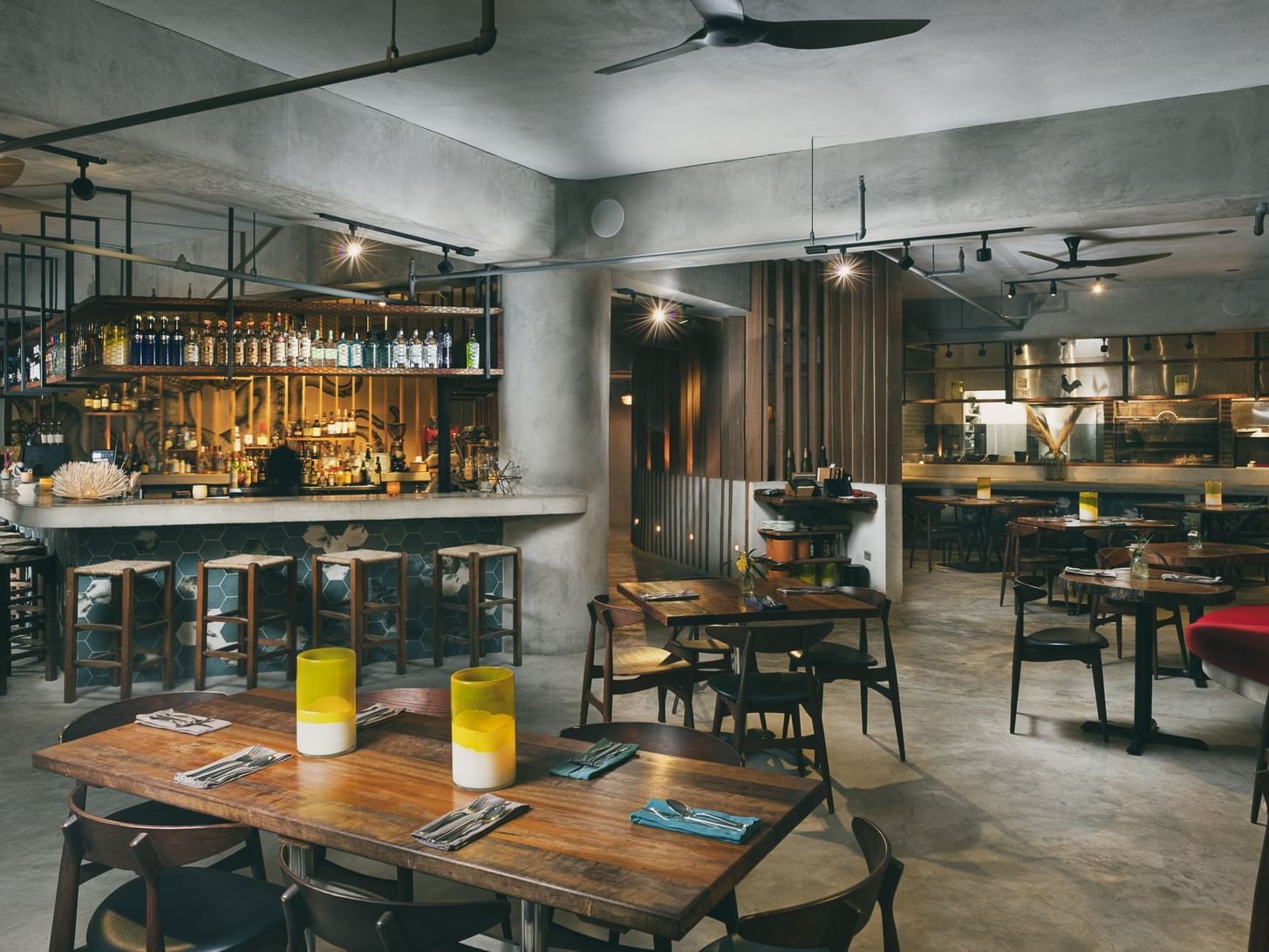 Modern industrial-style Placita Restaurant with concrete walls, open kitchen, bar, and wooden tables at El Blok in Vieques.
