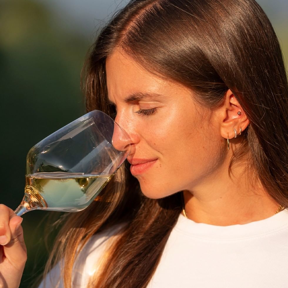 Frau genießt einen Schluck Wein aus einem Glas bei der PURO Wein Kollektion.