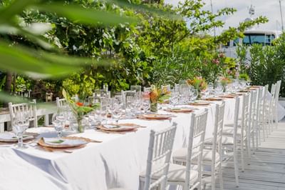 Long outdoor banquet table set with white chairs among Roatan, Honduras wedding venues at Barefoot Cay Resort & Marina
