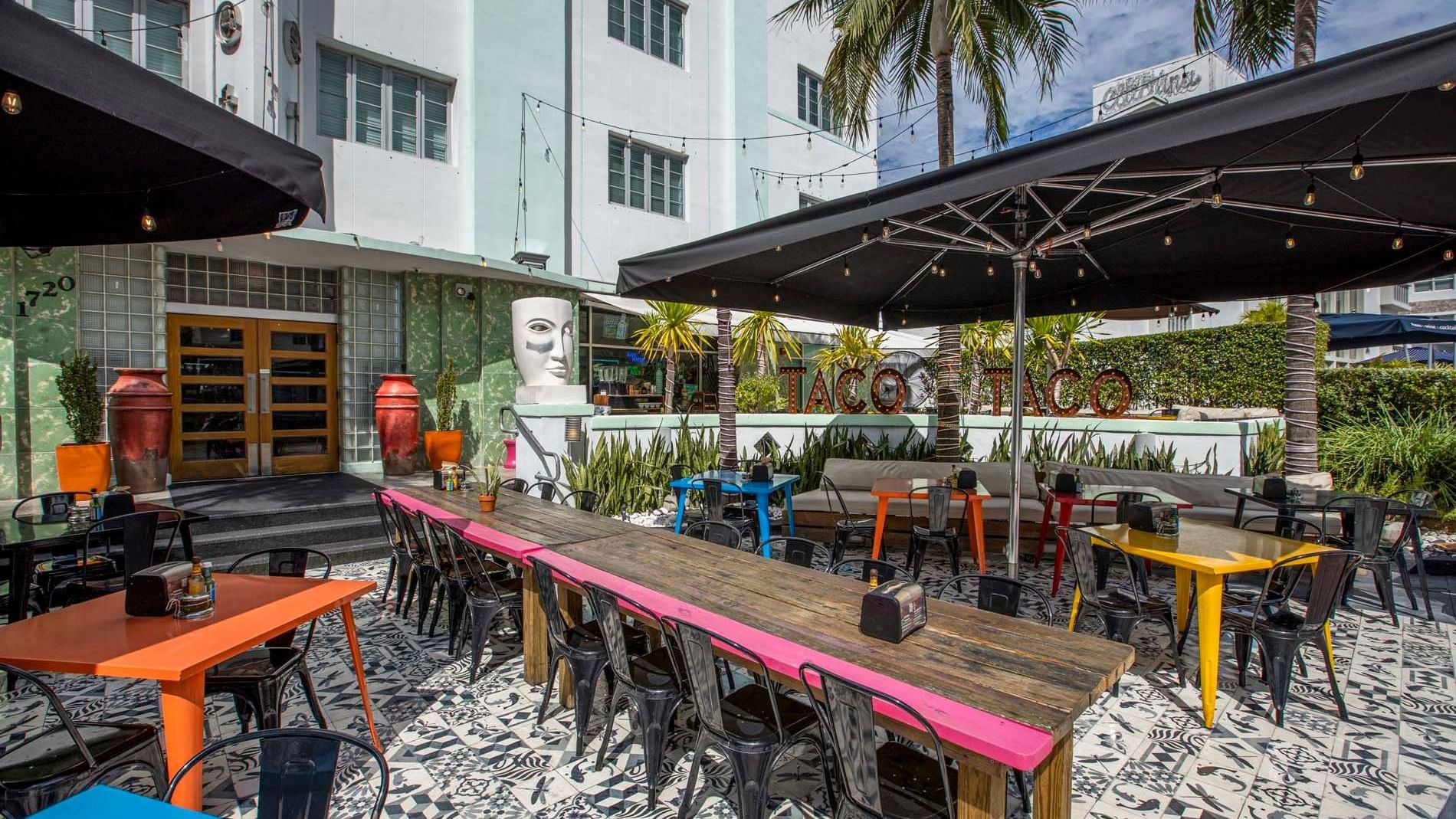 an outdoor dining area with tables and chairs under umbrellas