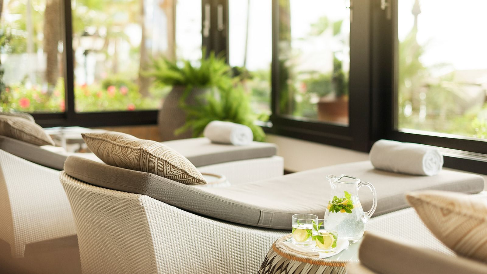 Relaxing lounge area with cushioned daybeds by large windows at the Marbella Club