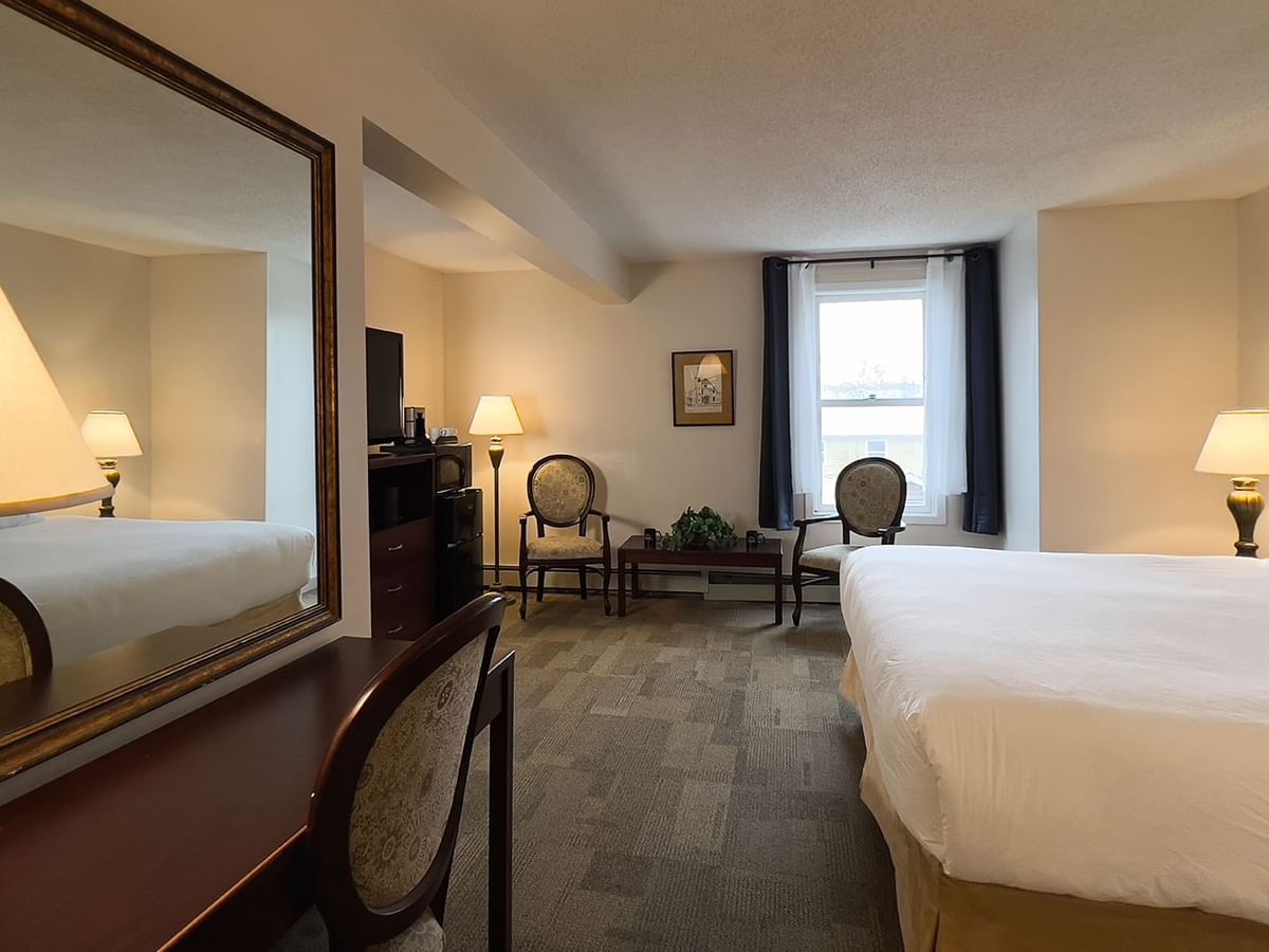 Bedroom suite with bed, mirror, window, chair, tv, and table