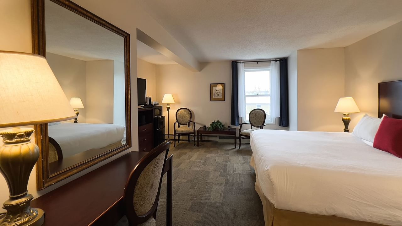 Bedroom suite with bed, mirror, window, chair, tv, and table