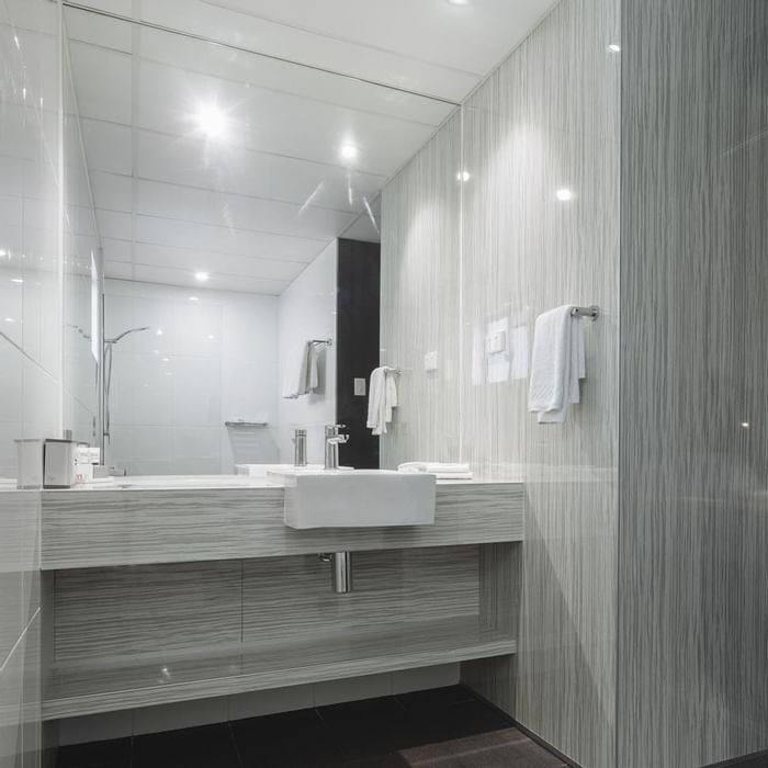 Modern bathroom featuring glass shower and vanity with a large mirror in Premium Room at Mercure Hotel Townsville