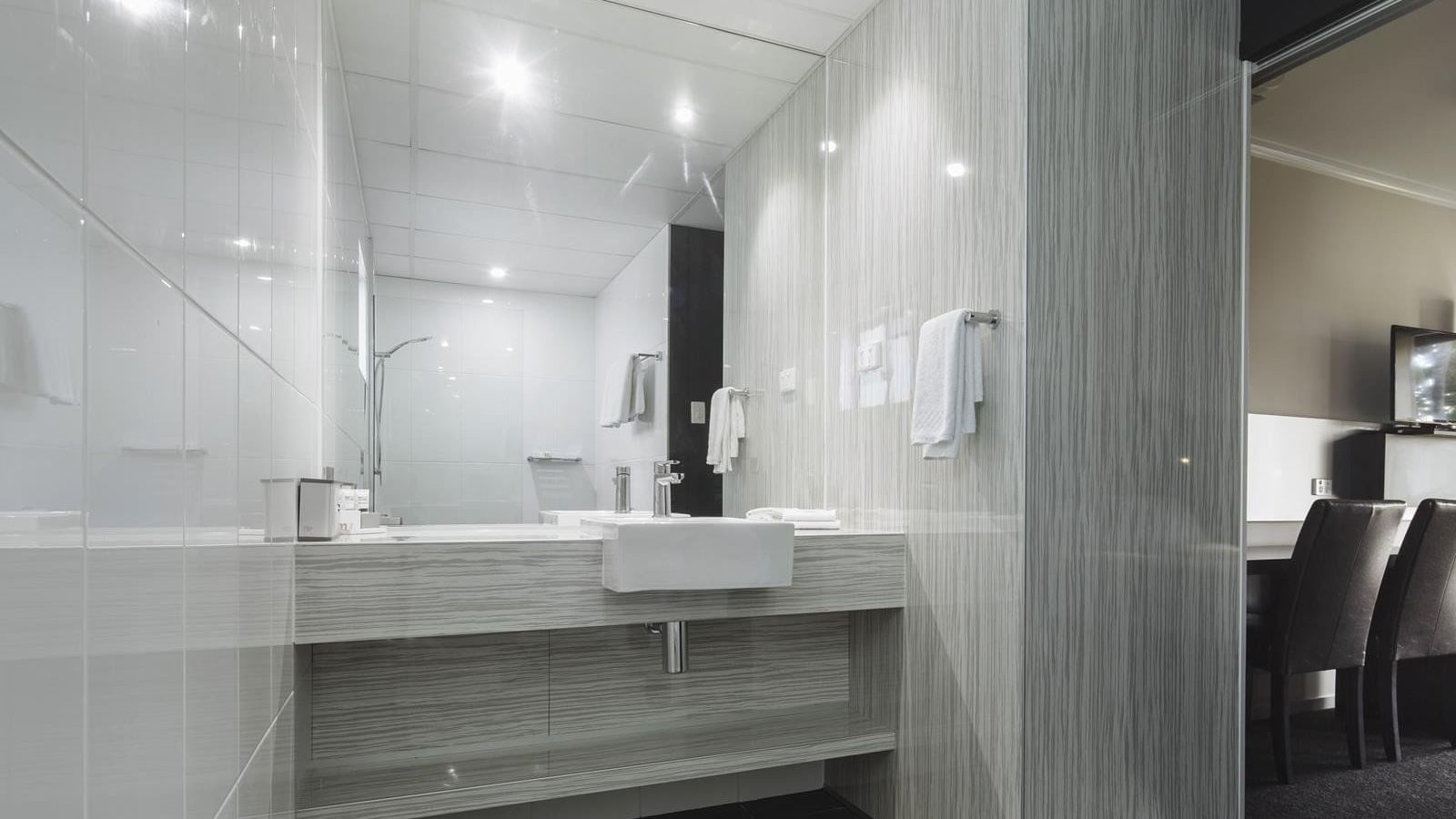 Modern bathroom featuring glass shower and vanity with a large mirror in Premium Room at Mercure Hotel Townsville