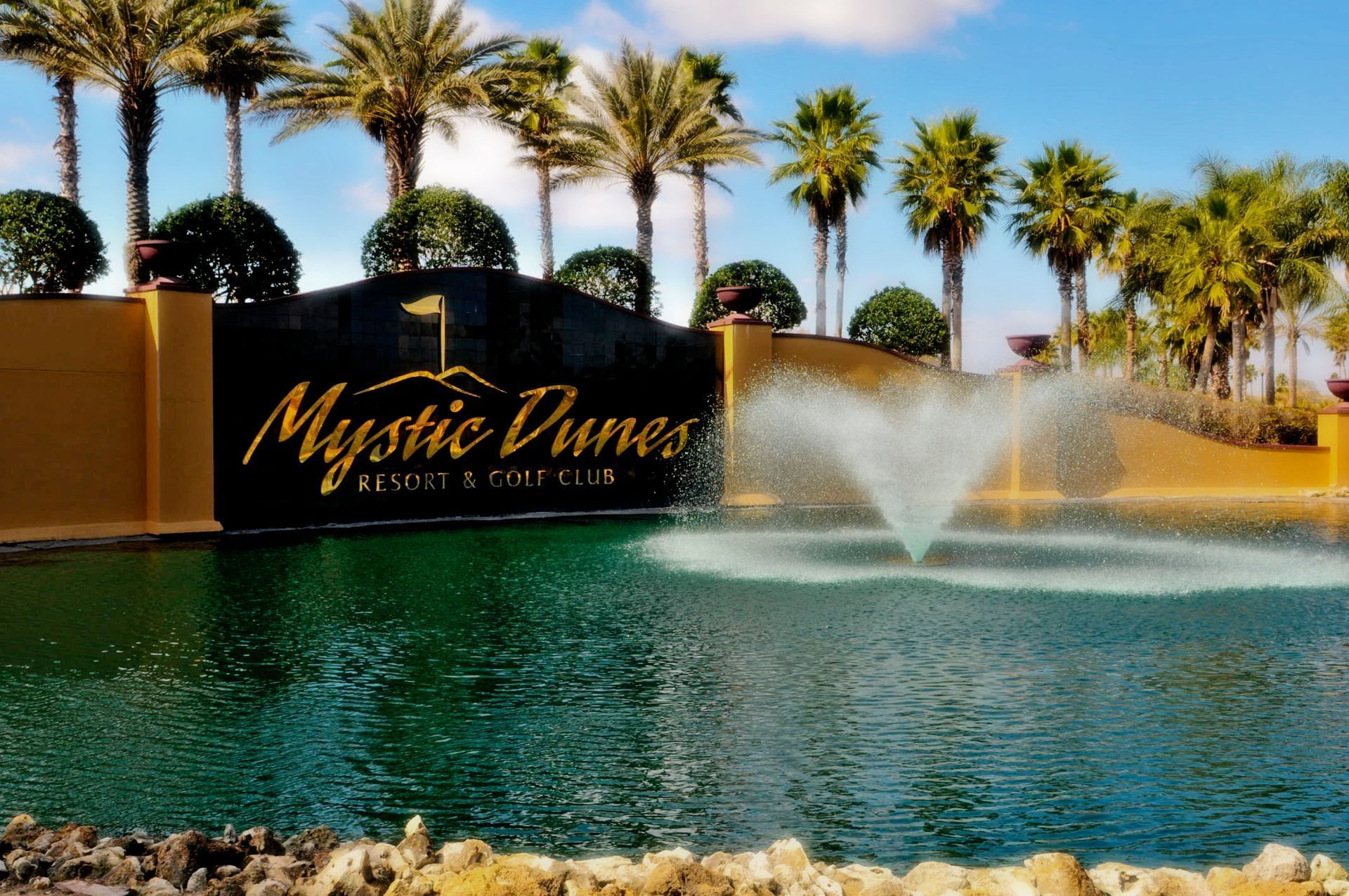 Mystic Dunes Resort sign at the entrance with a pond