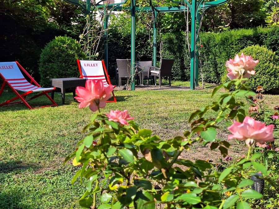 Two Lillet-branded deck chairs and a small black table in a lush garden at Warwick Reine Astrid - Lyon