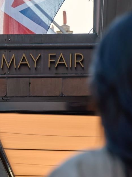 Woman with dark hair standing in front of The May Fair Hotel in London.