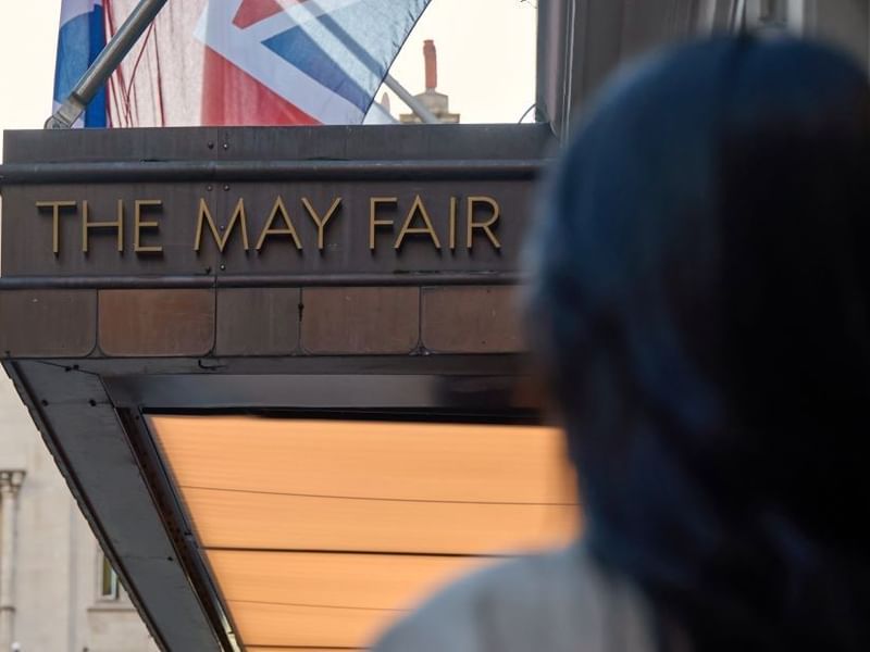 Woman with dark hair standing in front of The May Fair Hotel in London.