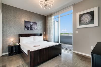 room with wooden bed frame, white bed and balcony